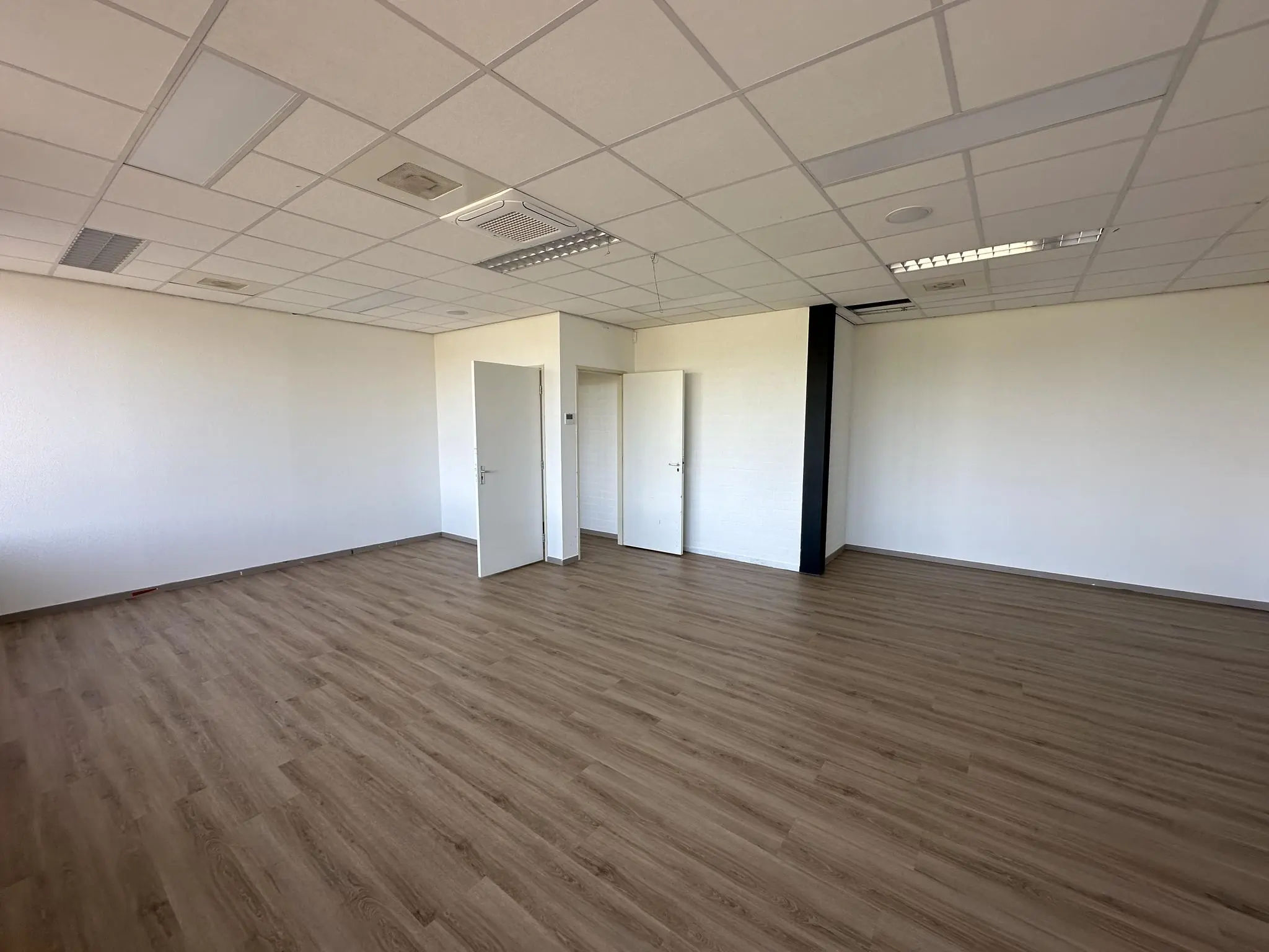 Leeg kantoor met houten vloer en systeemplafond aan de Van der Hagenstraat.